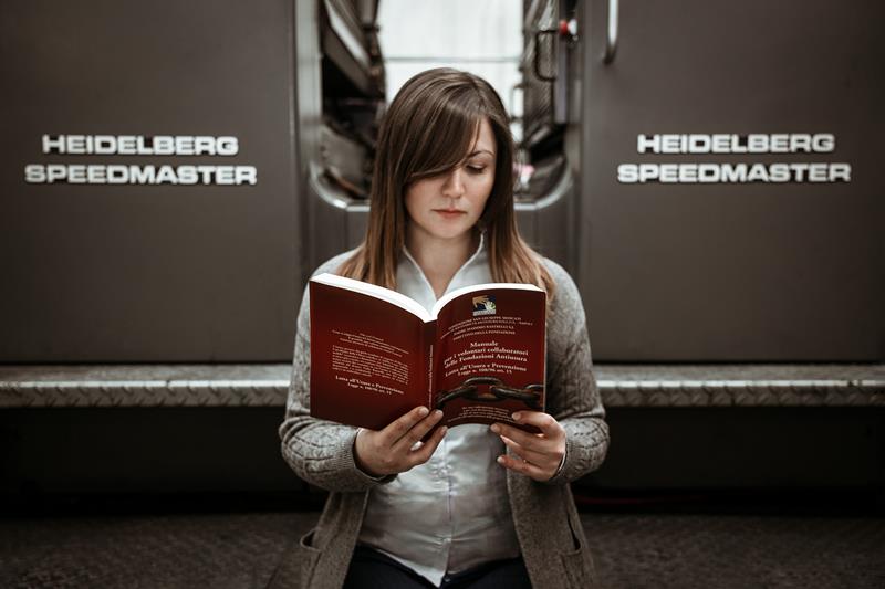 donna che legge un libro seduta su un heidelberg speedmaster